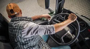 een vrachtwagenchauffeur leunt uit zijn raam om beter zicht te hebben op de linkerkant van zijn truck tijdens zijn manoeuvre