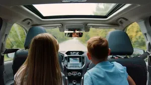 2 kinderen op de achterbank van een auto leunen naar voor om mee te kijken door de voorruit