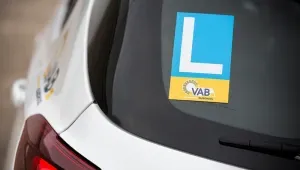 closeup van de achterruit van een witte auto met een L-sticker van VAB-Rijschool erop