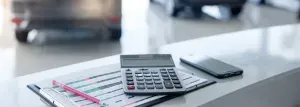 op de balie in een autoshowroom ligt een clipboard met financieringsopties, een rekenmachine, potlood en gsm