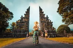 vrouw met hoedje en rugzak die naar een monument toewandelt in Bali