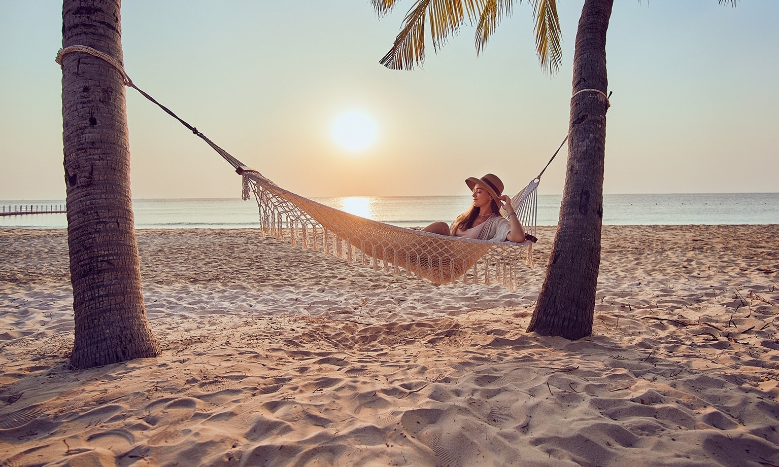 Vrouw in hangmat op het strand. Bescherm jezelf en je voertuig op reis met VAB.