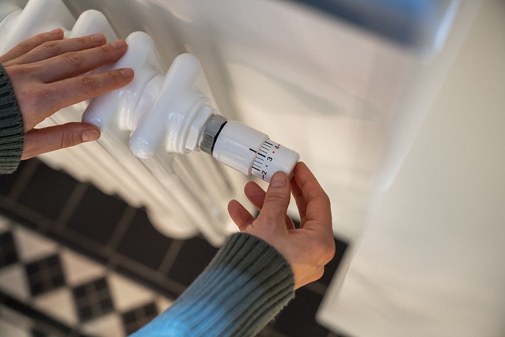 closeup van een radiatorknop waar een persoon aan draait