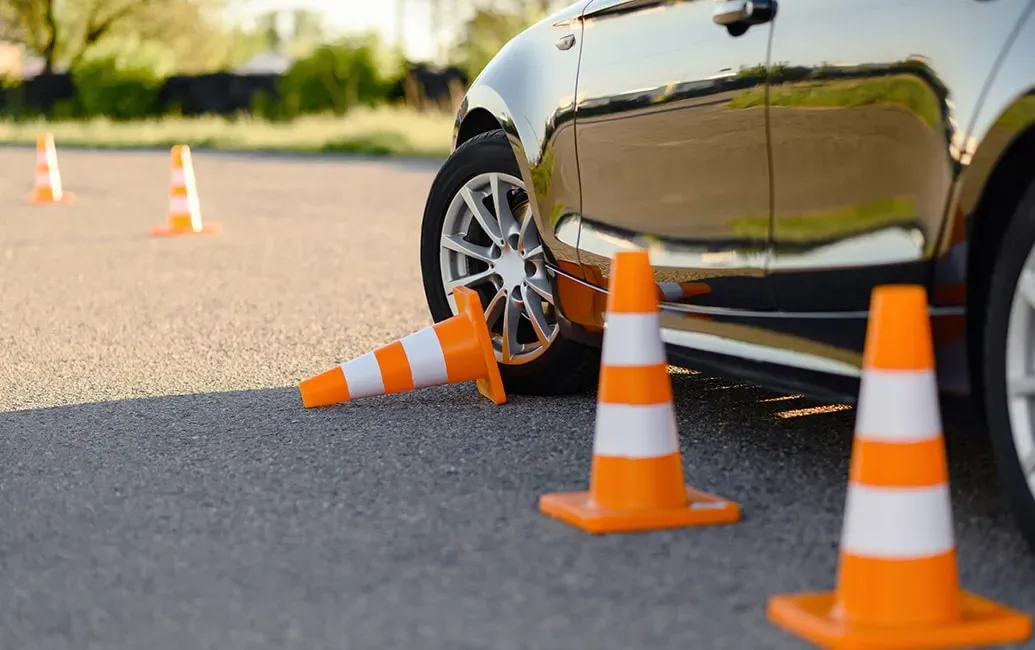 een auto die tijdens een training langs enkele kegeltjes rijdt maar er eentje over gestoten heeft