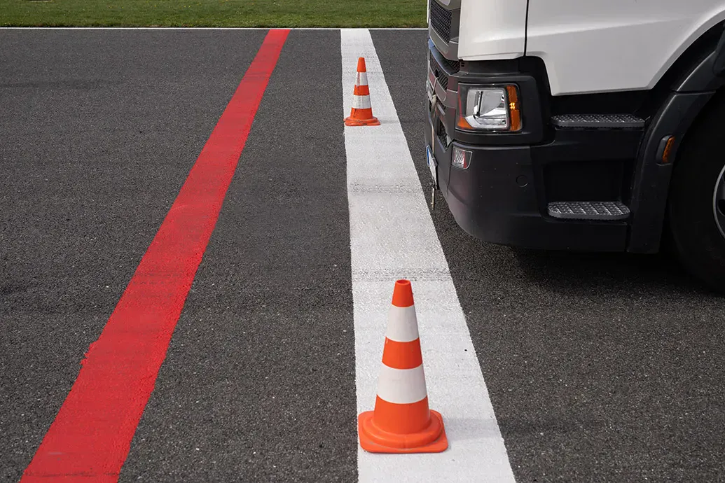 vrachtwagen stopt tijdens een rijles aan een stopstreep met 2 kegeltjes op