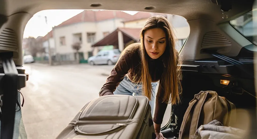 vrouw laadt bagage in de koffer van een wagen
