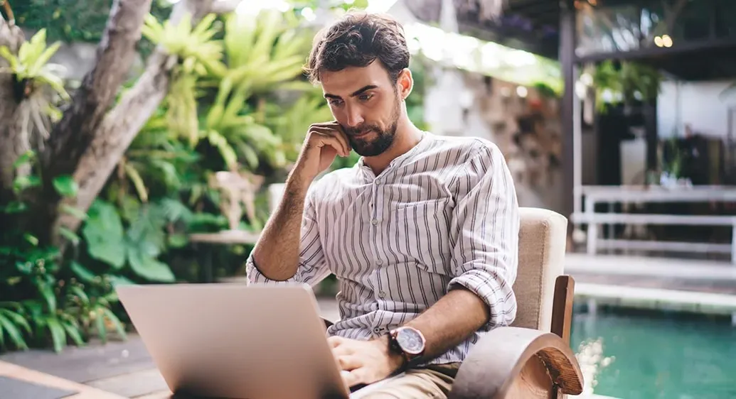 man kijkt naar laptopscherm in een tropische omgeving