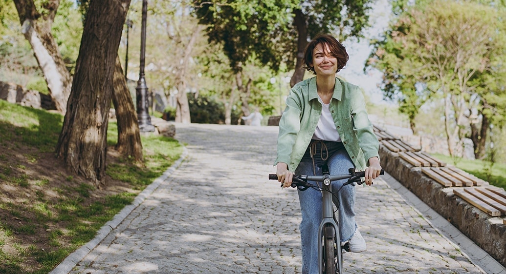 vrouw met groene blouse fiets in een park met veel groen en bomen