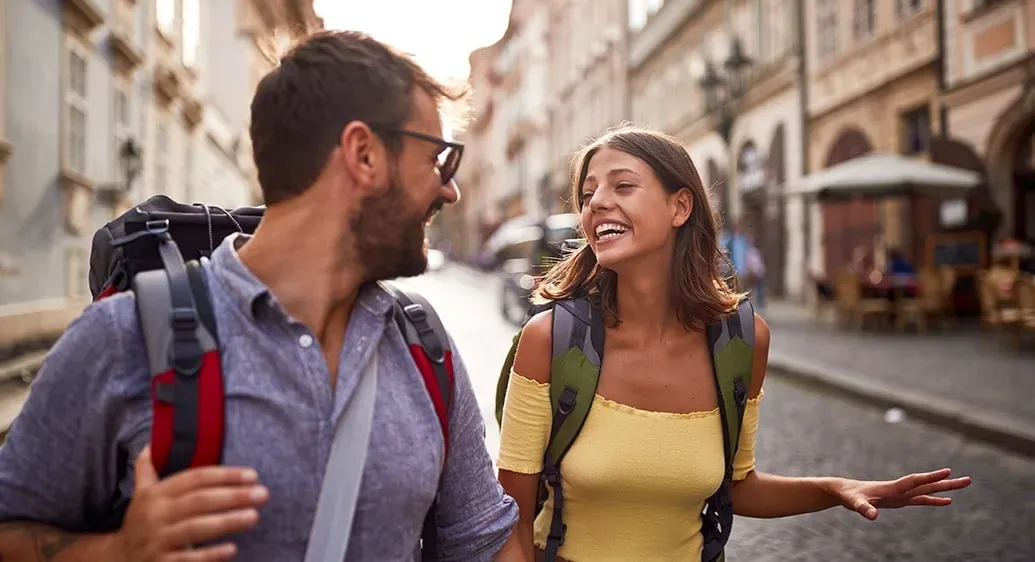 man en vrouw met rugzakken lopen rond in een zuiderse stad