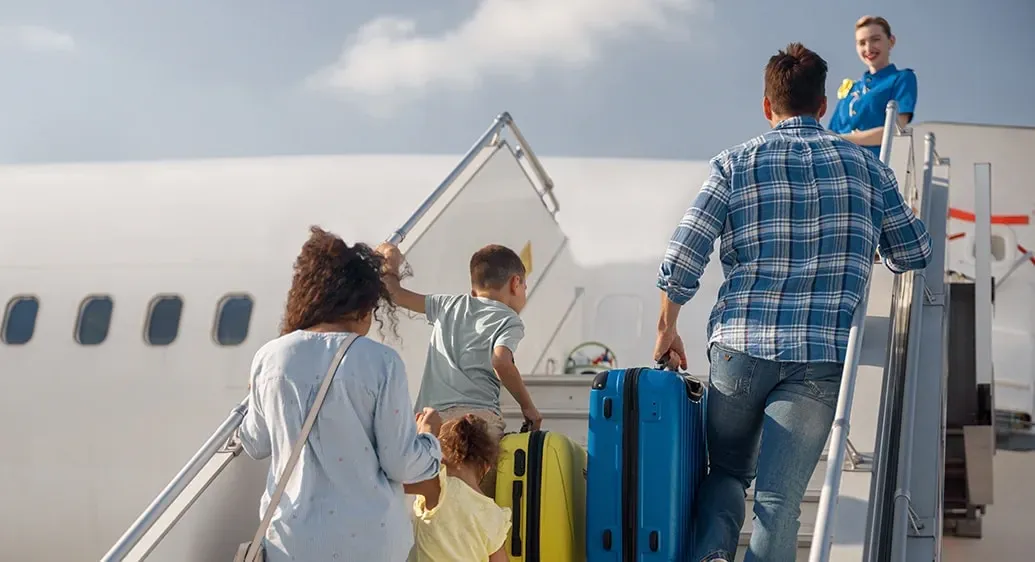 vader en moeder met 2 kinderen gaan de trap van een vliegtuig op om in te stappen