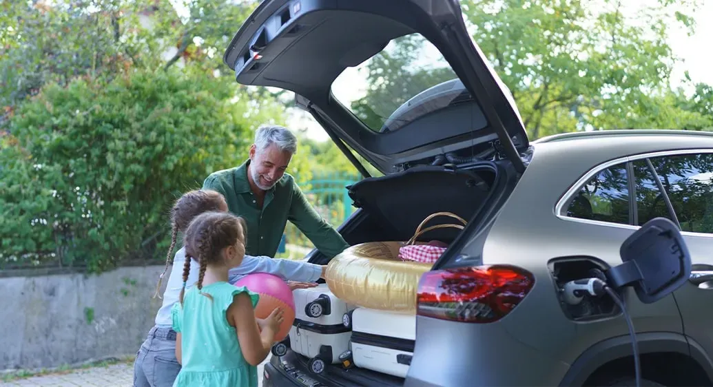 man en twee jongen meisjes laden koffers in de auto