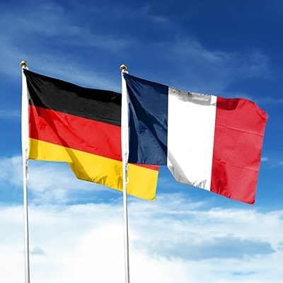 duitse en franse vlag aan vlaggenstokken met blauwe lucht op de achtergrond