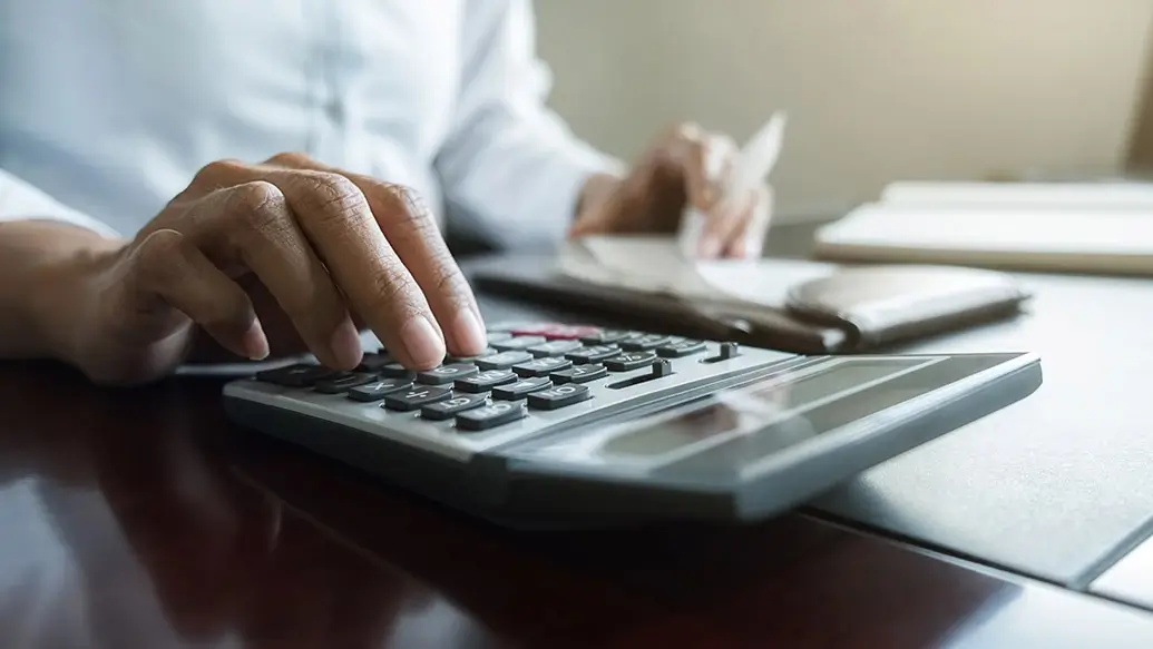 closeup van een man die een bereking maakt op een rekenmachine