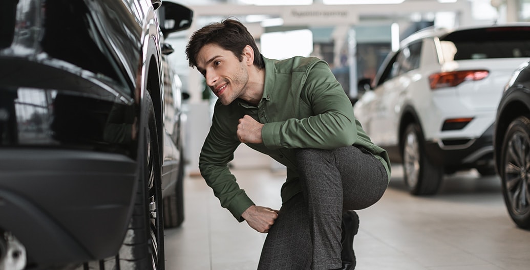 een man bekijkt een auto van dichtbij in een showroom