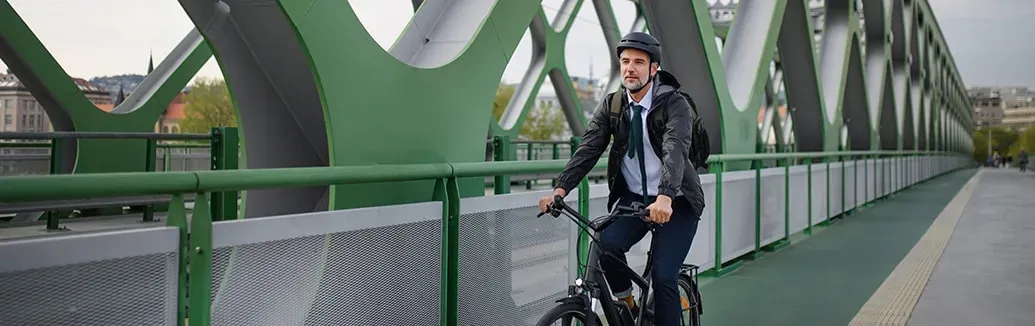 een man van middelbare leeftijd fietst over een groene stalen brug
