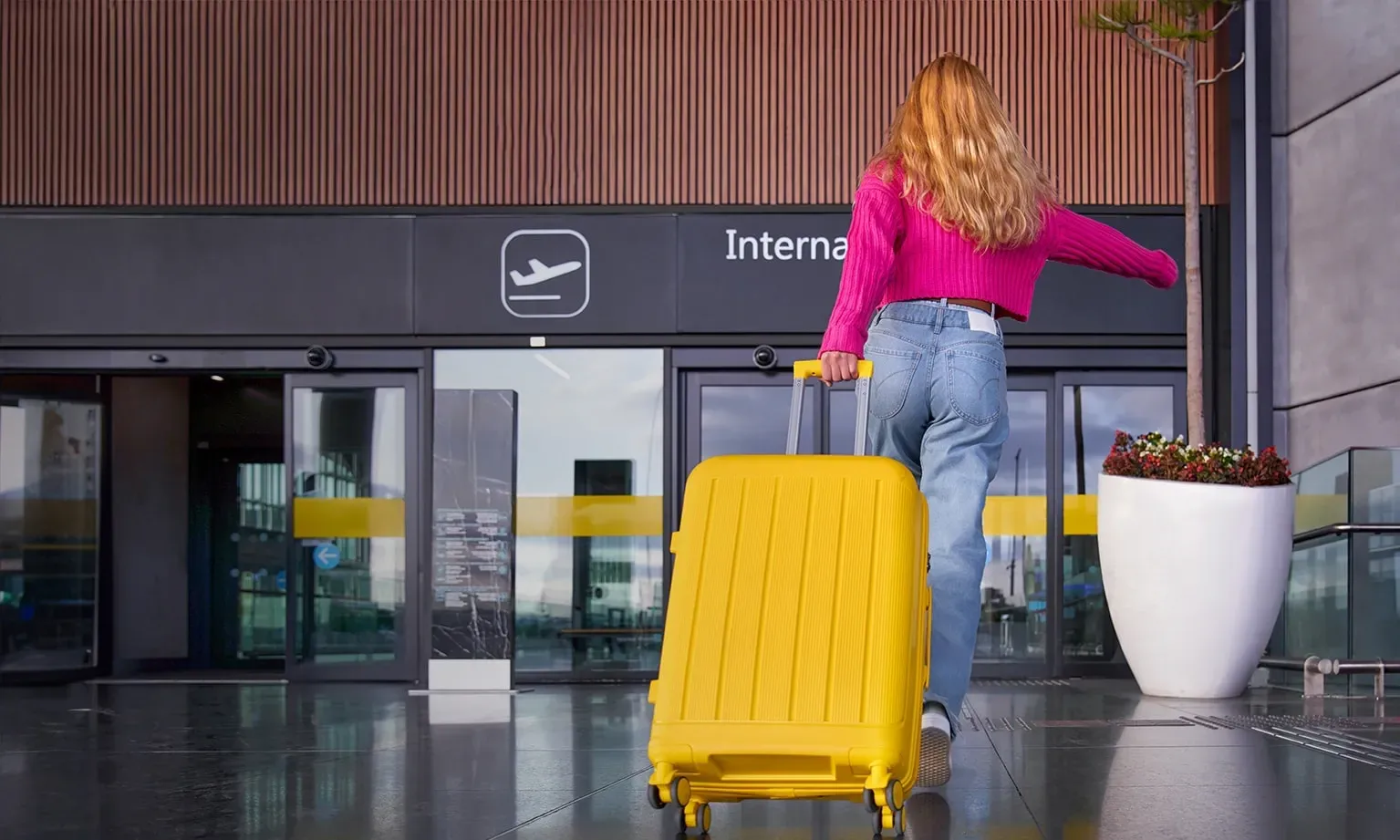Vrouw stapt de luchthaven binnen met een valies