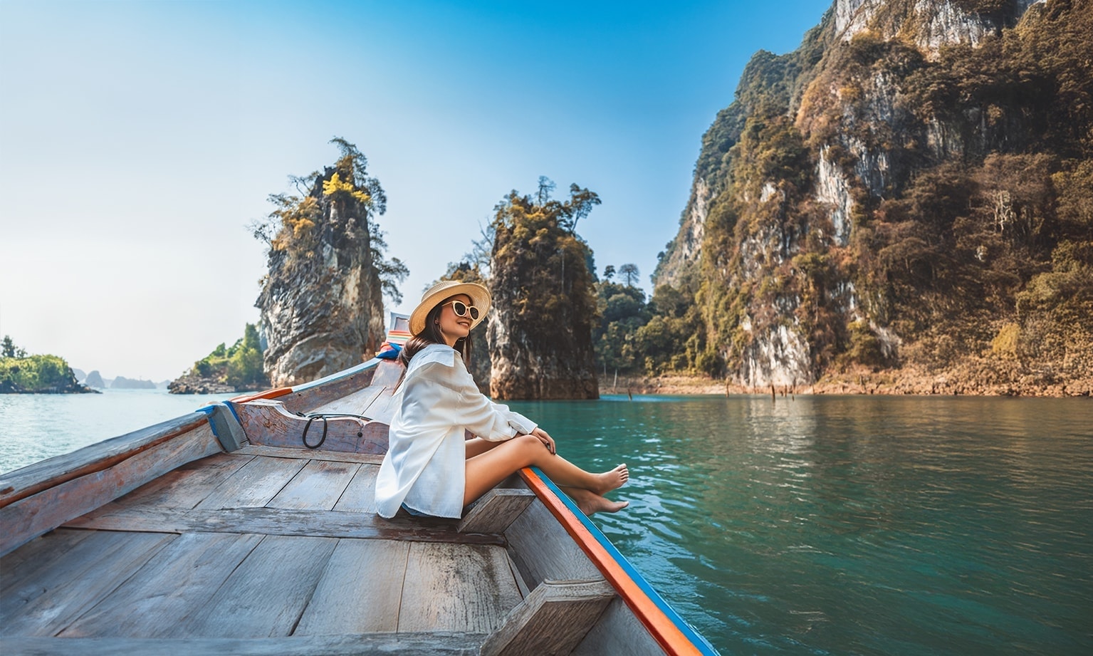 Vrouw in een bootje op een rivier met bergen op de achtergrond 